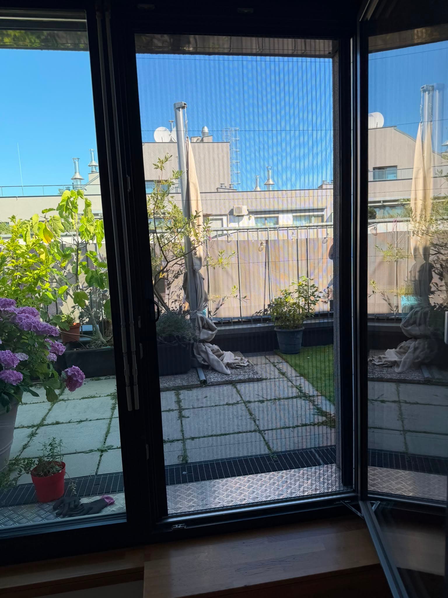 Plissee-Insektenschutz an einer Terrassentür mit Blick auf die Dachterrasse